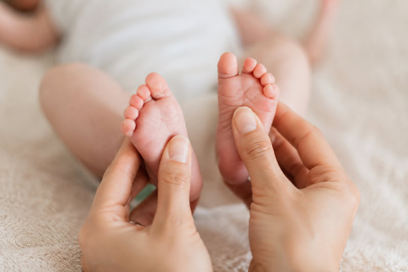 Pieds de bébé massés par les mains d'un parent